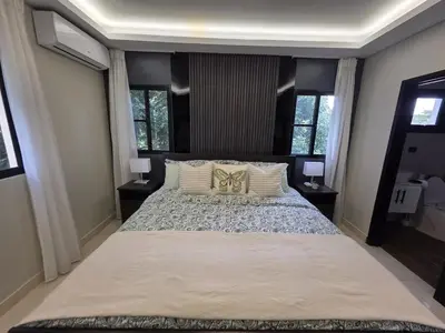 a large bed in a bedroom with two windows at La Elegancia in Canabacoa