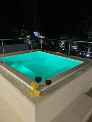 a swimming pool at night with two glasses of wine at MeliT in Las Terrenas