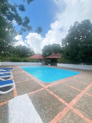 a swimming pool in a yard with chairs and trees at Private Suite in Casa de Campo in La Romana