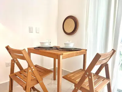 a wooden table with two chairs and a hat on the wall at Beachside Studio with Pool, Steps to Playa Bonita in Las Terrenas