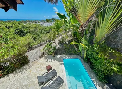 an image of a swimming pool with two chairs and the ocean at Hilltop Dominican Villa with Pool and Big Terrace in Las Terrenas