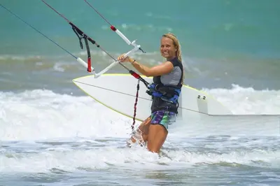 a woman is standing in the water on a surfboard at Space Freedom Connection in Sosúa