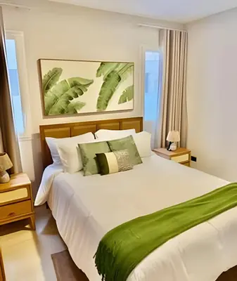 a bedroom with a large white bed with green pillows at Garden Breeze 1 By Advantage Club
