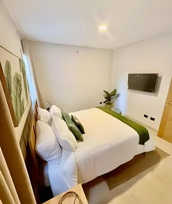 a bedroom with a white bed and a tv at Garden Breeze 1 By Advantage Club