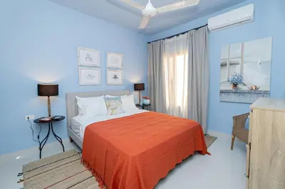a blue bedroom with a bed with an orange blanket at Caribbean Pearl 2BR Sunshine Bayahíbe in Bayahibe