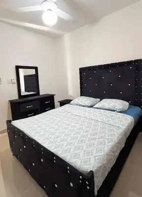 a bedroom with a bed with a black headboard and a television at Apartment near the airport in Boca Chica