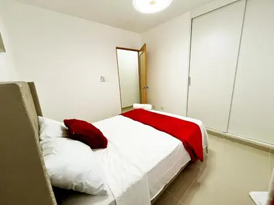 a bedroom with a white bed with a red blanket at Ideal space for the family in Boca Chica