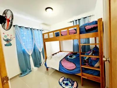 a bedroom with two bunk beds with blue curtains at Ideal space for the family in Boca Chica