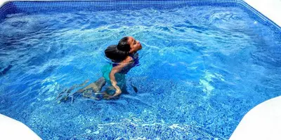 a woman is in a pool of blue water at the Count of Villa Rosa in La Ceiba