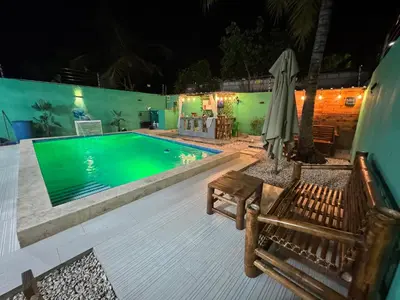 a swimming pool at night with a table and an umbrella at Villa yaya 1 in Boca Chica