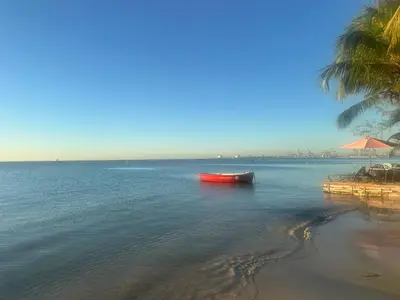 a red boat in the water next to a beach at Beachfront - Stunning View in Boca Chica