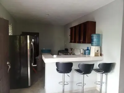 a kitchen with three bar stools and a refrigerator at Casa Ramona in Las Galeras