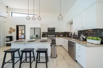 a large kitchen with white cabinets and bar stools at Peace Design Exclusivity in Sosúa