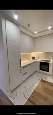 a white kitchen with white cabinets and a black microwave at Sirius apartment in Santo Domingo