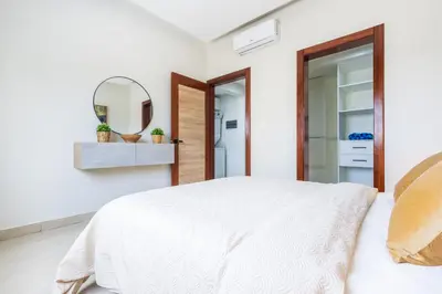 a bedroom with a white bed and a mirror at 2BR Tropical Escape - Private Terrace, BBQ, Pool, Walk to Beach in Punta Cana