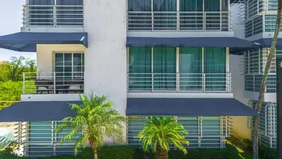 a tall building with palm trees in front of it at Resort Villas | 2 hab con piscina y playa in Juan Dolio