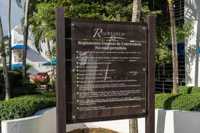 a sign in front of a park with bushes at Resort Villas | 2 hab con piscina y playa in Juan Dolio