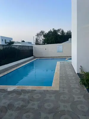 a swimming pool next to a white building at res Montesino in San Felipe de Puerto Plata