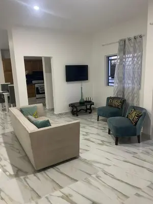 a living room with a couch and two chairs and a tv at res Montesino in San Felipe de Puerto Plata
