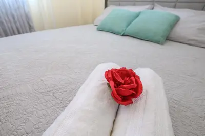 a red rose sitting on top of a white bed at Edificio Amber in San Cristóbal