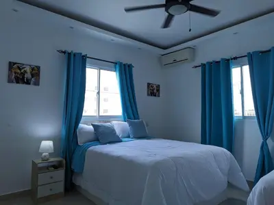 a blue bedroom with a bed with blue curtains at Azure Breeze Hotel in Bayahibe