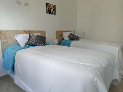 two beds in a room with white sheets and pillows at Azure Breeze Hotel in Bayahibe