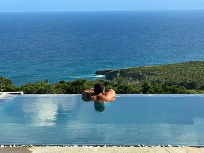 a man in a swimming pool overlooking the ocean at AguaSanta, Breeze & Views in Palmarito