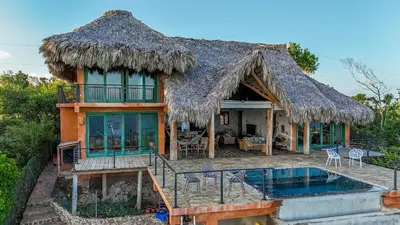 a house with a thatched roof and a swimming pool at AguaSanta, Breeze & Views in Palmarito