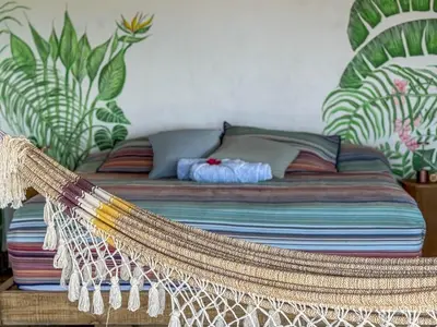 a bed with a hammock in a room with plants at AguaSanta, Breeze & Views in Palmarito