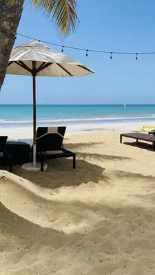 a beach with a chair and an umbrella on the sand at Stylish 1BR, Pools & Walk to Beach - Sublime in Las Terrenas