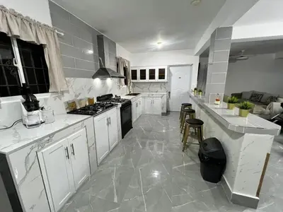 a large kitchen with white cabinets and appliances at Villa Medrano Home in Punta Cana