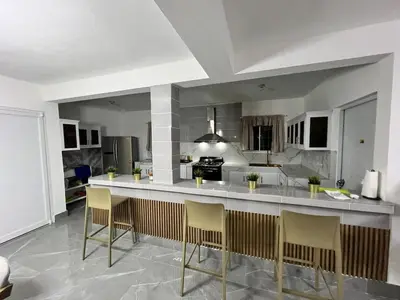 a kitchen with a large island with bar chairs at Villa Medrano Home in Punta Cana