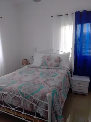 a bedroom with a bed and a window with blue curtains at Villa del mar in Bayahibe