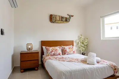 a bedroom with a bed and a nightstand and a window at Armonía Las Terrenas in Las Terrenas