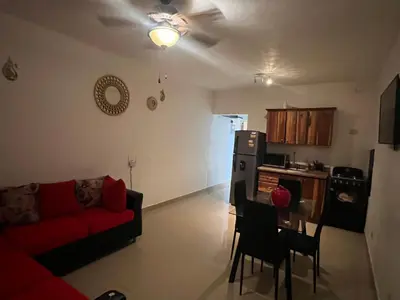 a living room with a red couch and a kitchen at Bienvenue chez soi in Boca Chica