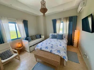a bedroom with a bed and a couch and windows at Juan dolio Penthouse, beach access 3BR Salitre Tower front of Club Hemingway in Juan Dolio