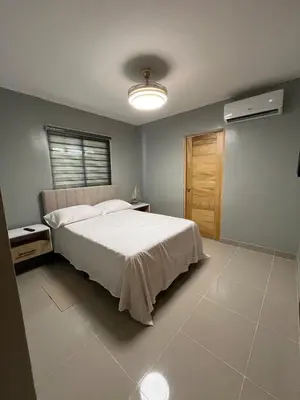a bedroom with a large white bed and a window at Moderno Apartamento Boca Chica, 5 minutos del Aeropuerto in La Caleta