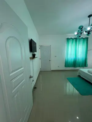 a white room with a bed and a door and a television at Paisible et confo in Boca Chica