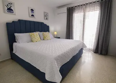 a bedroom with a bed with a blue headboard and a window at Casa Jobo Scenic ViewsPrivate Pool TablePool in San Felipe de Puerto Plata