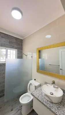 a bathroom with a toilet and a sink and a mirror at Elegante Casa Estrella Marina 117 Pool BBQ in La Romana