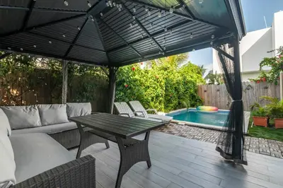 a patio with an umbrella and a table and a pool at Hermosa villa con piscina privada, jacuzzi y playas cercanas in Punta Cana