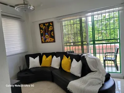 a black couch with yellow pillows in a living room at Apartamento dos dormitorios en la zona colonial in Santo Domingo