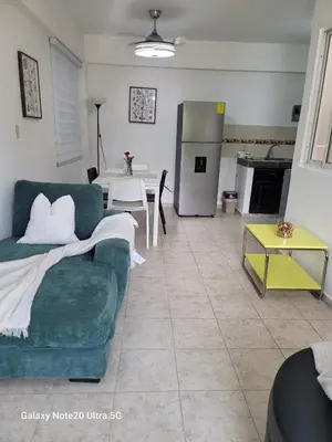 a living room with a green couch and a kitchen at Apartamento dos dormitorios en la zona colonial in Santo Domingo