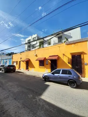 a blue car parked in front of a yellow building at Apartamento dos dormitorios en la zona colonial in Santo Domingo