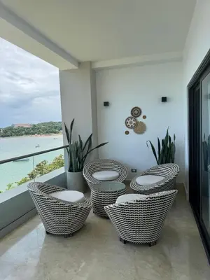 a balcony with wicker chairs and a view of the ocean at Acogedor apartamento en Samaná con vista al mar in La Aguada