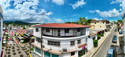 a building with a red roof on a city street at Brisas de Jarabacoa in Jarabacoa