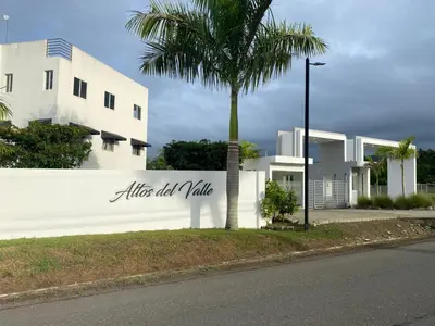 a white building with a palm tree in front of it at Peaceful Cottage in Santiago de los Caballeros