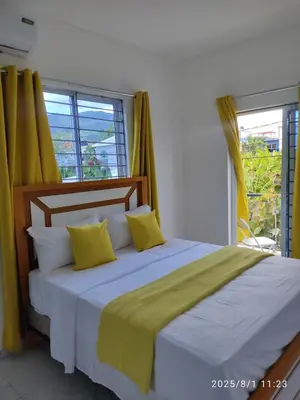 a bedroom with a large bed with yellow curtains at Apartament with Beautiful Mountain View in Puerto Plata