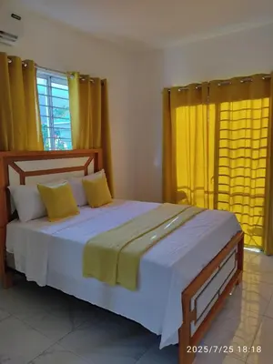 a bedroom with a large bed with yellow curtains at Apartament with Beautiful Mountain View in Puerto Plata