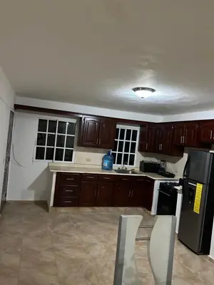 a kitchen with wooden cabinets and a black refrigerator at Villas Maniscalco in Camú